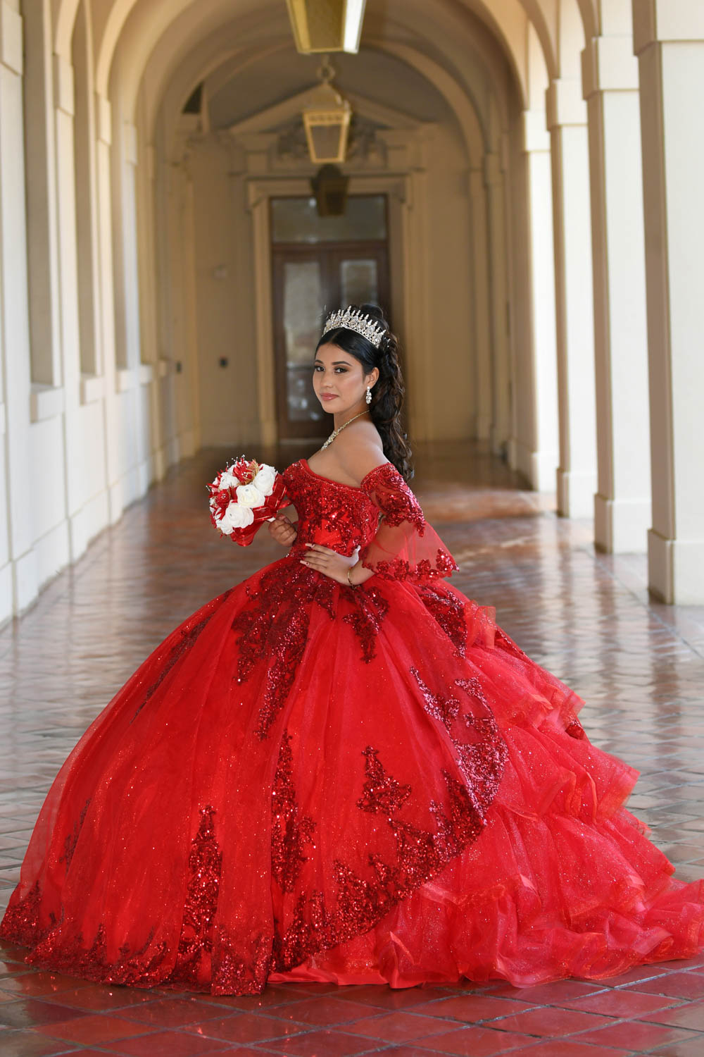 Quinceañera con vestido rojo entre arcos