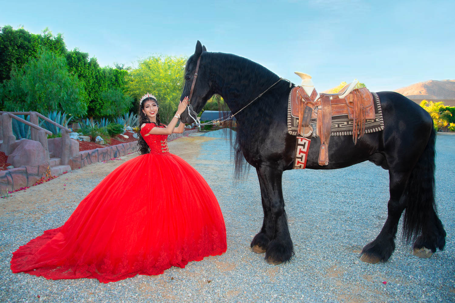 Quinceañera con vestido rojo junto a un caballo negro