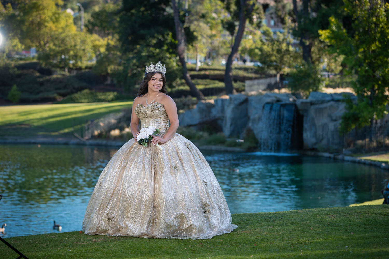 Quinceañera con vestido dorado junto al lago